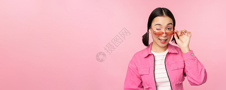 时髦的现代亚洲女孩触摸太阳镜 穿粉红色 以工作室背景作姿势 复制空间Copy space办公室情绪促销广告企业家购物成人大学商业背景图片