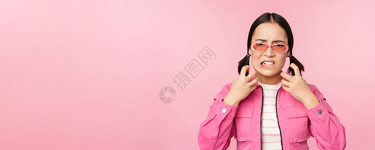 愤怒 愤怒的韩国成年女模特的形象 握着拳头 大喊大叫 愤怒地尖叫 站在粉红色背景上学生女孩情感企业家黑发广告办公室标识工作女士背景图片