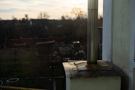 一座被毁房屋屋顶上的老旧生锈铁烟囱建筑管道房子漏斗蓝天烟道空气材料天空风化图片