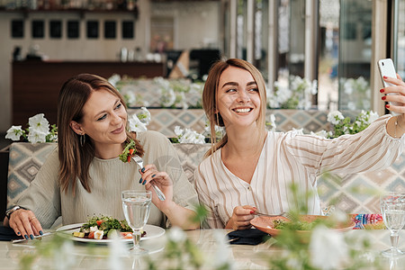 两位女性在吃午餐时自食其乐的女朋友在餐厅里吃沙拉会议成人女孩早餐朋友们咖啡店白色朋友图片