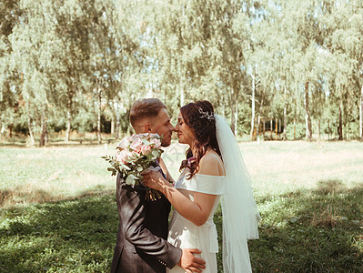 幸福的结婚夫妇在植物园公园散步 粮食效果真品婚礼面纱新人丈夫热情花束家庭乐趣裙子拥抱背景图片