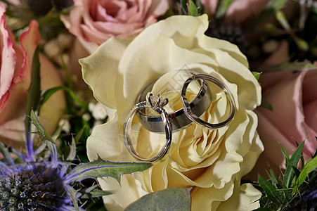 白金和钻石婚礼及订婚戒指与白玫瑰和粉红玫瑰布束图片