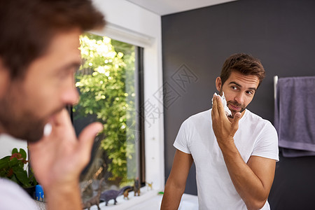 剃须膏首先保护我的皮肤 一个英俊的男人在家里的浴室里把剃须膏涂在脸上的镜头图片