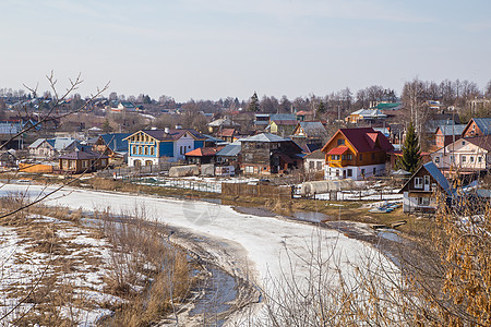 一条冰冻的河延伸至远处 在河岸上的一个村庄图片