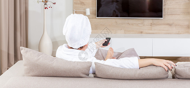 女人坐在沙发上 头部有毛巾闲暇控制假期女士休息房子体积长椅电影娱乐图片