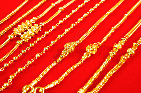 红色天鹅绒布上的金项链宝石手镯魅力金属衣领吊坠戒指支架金融女人味图片