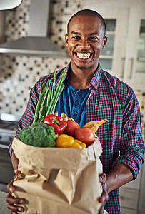一位英俊的年轻人在家里厨房里拿着一袋杂货 被剪裁成肖像 (笑声) 我开始吃更健康的食物图片