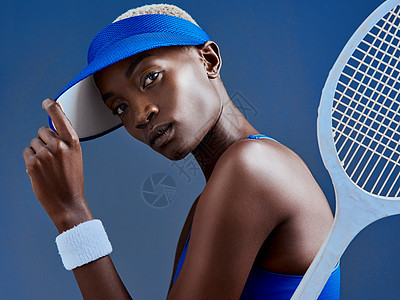 演播室拍到一个运动的年轻女子 用网球拍打蓝底 装扮成网球场图片