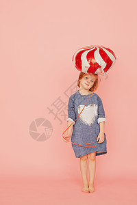 一个兴奋的漂亮小女孩的肖像 庆祝生日 并拿着气球 在粉红色背景上手牵着女孩喜悦展示乐趣丝带蛋糕礼物庆典孩子童年图片