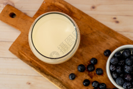 桌子上木板上的蓝莓旁边的一杯牛奶的最顶端视图 健康饮食 请务必注意玻璃木头酸奶食物薄荷早餐饮食奶制品奶油乡村图片