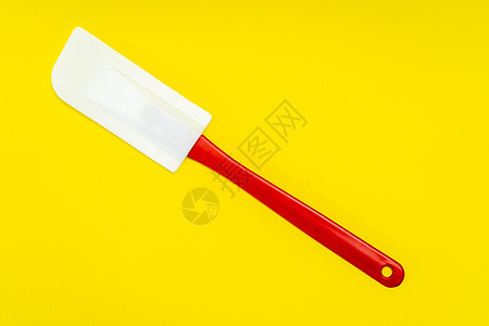 由硅酮和在黄色表面绝缘的塑料制成的红色和白色厨房排气管美食勺子用具配件工具糕点厨师家庭工作室服务器图片