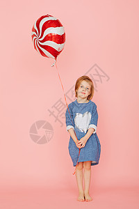 一个兴奋的漂亮小女孩的肖像 庆祝生日 并拿着气球 在粉红色背景上手牵着童年盒子喜悦庆典孩子丝带棉花食物乐趣蜡烛图片