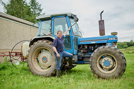 来我办公室看看吧 一个快乐的年轻农夫的肖像 在田野上站在他大农场拖拉机旁边农家男性乡村绿色成人工作全身农业国家生活图片