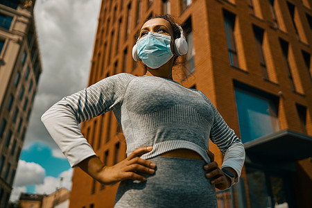 在城市培训时身戴面罩的健康健康妇女;背景图片