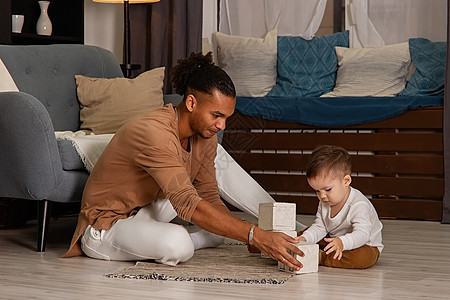 父亲和小儿子在房间里的地板上玩立方体图片