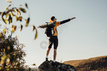 在日落时站在岩石顶端 男游牧人享受自由 独行三轮运动概念图片