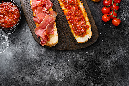 意大利番茄 熏火腿 火腿 火腿和奶酪意式烤面包 黑色深色石桌背景 顶视图平躺 带文本复制空间图片