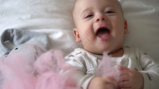 特写快乐顽皮的孩子 6 个月大 刚出生的男孩在白色柔软的床上沐浴后看着相机 宝宝睡前用玩具醒来的时间 童年 母亲 家庭 婴儿概念图片