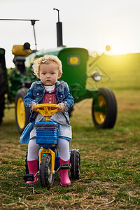 务农不适合胆小的人 一个可爱的小女孩在农场上骑玩具卡车的画像图片
