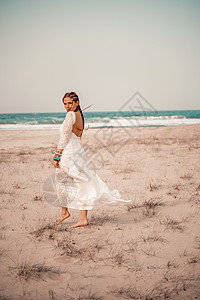 在海滩上穿白色长裙和银首饰的波霍风格模特儿 她的头发是编织的 手臂上有许多手镯女性珠宝配件婚礼女士成人女孩荒野钩针裙子图片