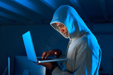 准备好与全世界分享您的个人信息 一名年轻男性黑客在黑暗中使用笔记本电脑的镜头图片