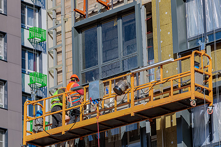 男性建筑工人在一个悬停的摇篮里 在大楼外墙上工作高度装配工工匠作品笼子装置都市现代人上班族镶板图片