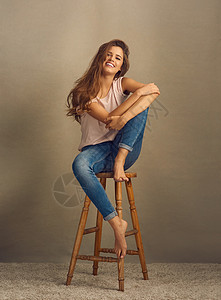 工作室拍到一位美丽的年轻女士坐在凳子上 站在一个普通背景的椅子上 她被拍到了图片