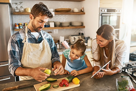 一起掌握新技术 两个快乐的父母和他们年幼的女儿一起在厨房里尝试新食谱的照片图片