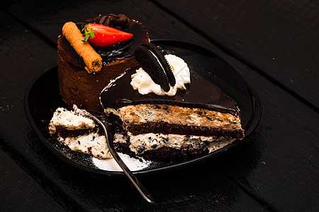 巧克力慕斯配草莓 巧克力棒和奶油芝士蛋糕配巧克力饼干 黑色盘子上的奶油饼干图片