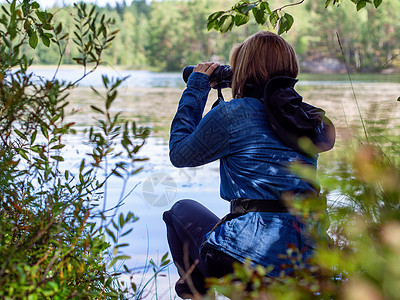 年轻女子通过双筒望远镜观察湖上的鸟儿 观鸟 动物学 生态学 自然研究 动物观察鸟类学秋鸟迁徙选择性聚焦 软聚焦图片