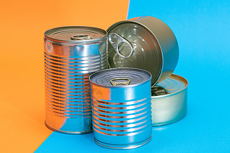 一组堆叠的锡罐 在蓝色和橙色分片背景上带有空白边缘食物不锈钢盒子蔬菜商品装罐产品养护密封罐金属背景图片