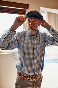 他是一位时尚的前辈 一位性格开朗的老人一边看着镜头一边试戴他的一顶帽子的画像图片