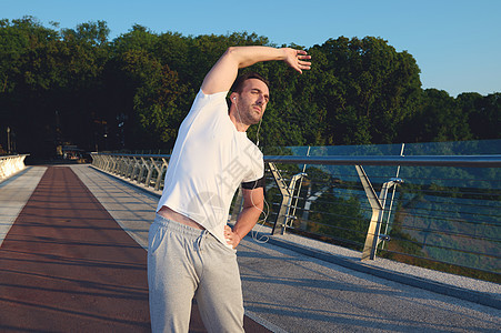 英俊的中年白人男子 运动员 运动员在户外锻炼 站在跑步机上 热身 在晨跑前伸展身体图片
