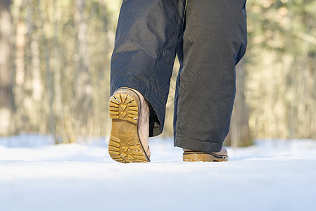 女人在冬季森林的雪上行走 专注独秀和雪动机赛跑者工作运动靴子跑步公园季节皮革耐力图片