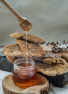 美味的蜂蜜从Wooden蜂蜜小甜点滴入玻璃罐和新鲜蜂窝背景美食石头液体金子味道黑石草药香气琥珀色健康饮食图片