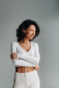 穿着白色运动服的笑笑着女人的肖像 以灰色背景突出显示教练女性运动装微笑运动员黑发男人健身房有氧运动体操图片