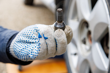 机械手在织布手套上架着车轮机损害劳动紧固件首都汽车螺纹线程螺栓休息安全图片