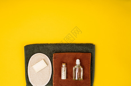 含有基本芳香油 毛巾和黄底肥皂的瓶子 在黄色背景上按摩玻璃产品卫生温泉芳香治疗擦洗洗澡奢华图片