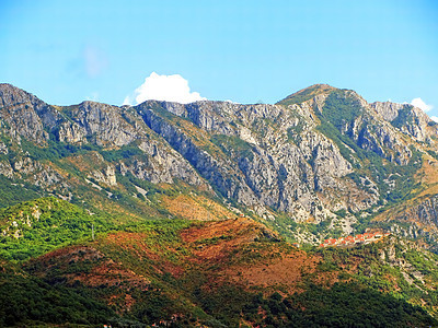 一堵山墙耸立在山谷之上 在阳光明媚的日子里 温暖的色调与山上的一个小村庄 山岩花岗岩农村旅游牧场国家日出山脉公园全景森林丘陵图片