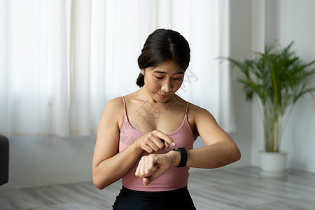 亚裔女性建立健身智能手表以在家健身的亚洲女性图片