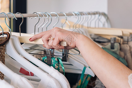 在时装店从衣架上捡衣服的女人的手 购物概念图片