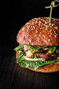 芝士汉堡加烤肉 奶酪 西红柿和黑木表面的黄瓜 广告理想面包乡村洋葱芝麻美食包子桌子酒吧牛扒木头图片