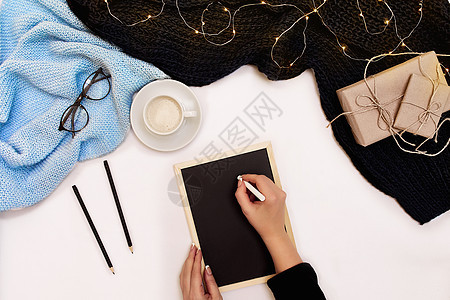 女人的手握着一件织成黑毛衣 紧靠白纸 从上到下看嘲笑行动办公室职场眼镜咖啡铅笔记事本活动杯子图片