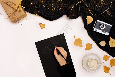 女人的手握着一件织成黑毛衣 紧靠白纸 从上到下看女性卡片杯子活动绘画眼镜桌子嘲笑行动季节图片