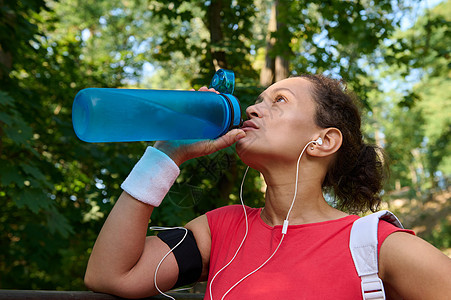 女运动员在户外艰苦运动锻炼后 用瓶装 清新和冲洗身体的水水提供饮用水图片