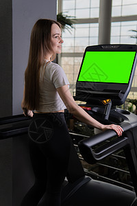 女性年轻跑步机在室内长度轮廓全运动 适合身体和机器有氧运动 设备的生活方式 慢跑回家图片