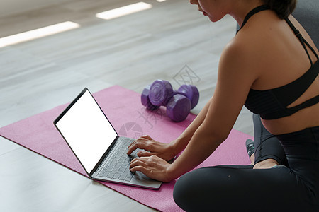 在家练习瑜伽的年轻女性在笔记本电脑在线课程中跟随教师 冷静和放松概念运动哈达地面房间班级运动员健康技术身体疼痛图片
