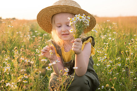 一个戴着草帽的金发小女孩拿着一束雏菊走在田野里 走在自然 自由和生态友好型生活方式中的概念金发女郎场地甘菊乐趣草本植物婴儿野生动图片