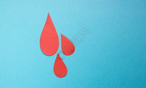 世界献血和血友病日的概念 蓝色背景的红色纸上的血滴 您可使用文本的位置图片