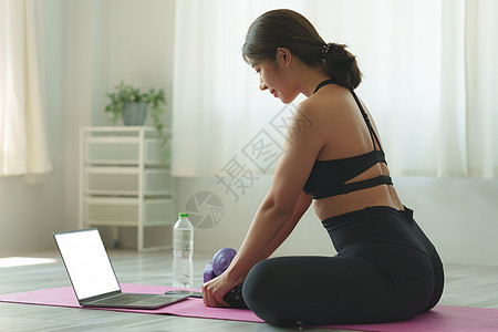 在家练习瑜伽的年轻女性在笔记本电脑在线课程中跟随教师 冷静和放松概念女士地面互联网技术房间身体姿势视频健康运动员图片